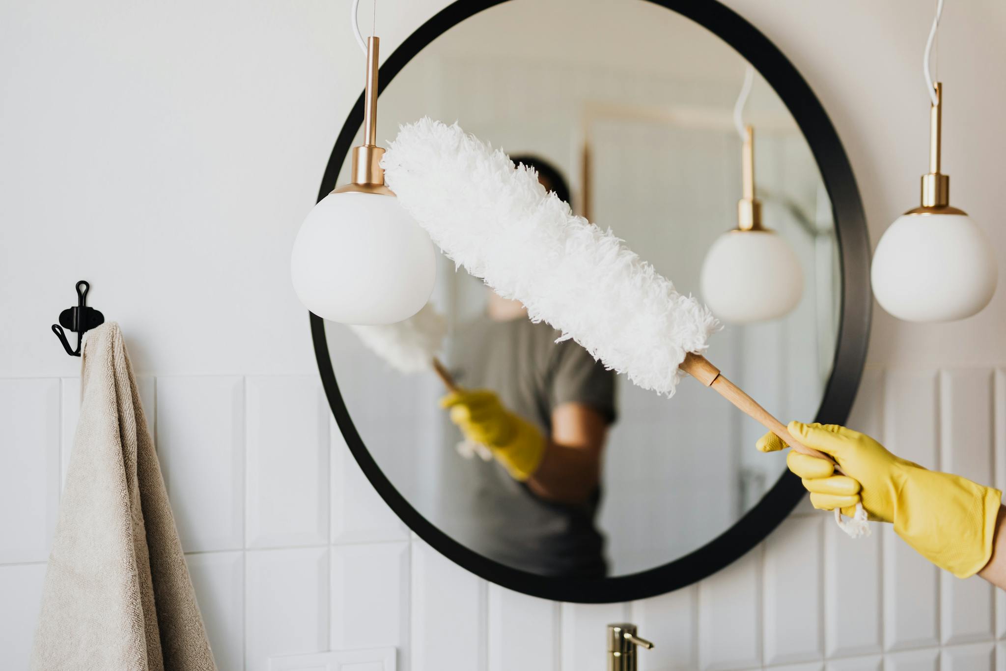 Crop woman dusting lamp during housework