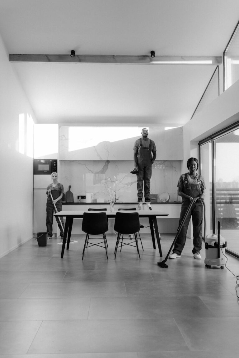 Grayscale Photo of People Standing Near Table